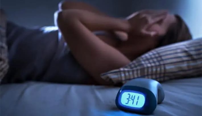A man sleeping on bed wearing a sleep apnea device